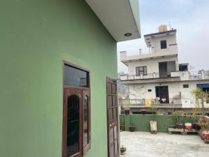 eine grüne Wand mit einem Fenster und einem Gebäude in der Unterkunft Hillsview Homestay in Rūpnagar