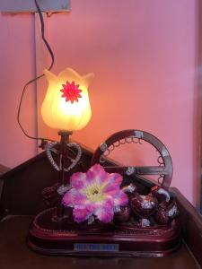 eine Lampe auf einem Tisch mit einem Korb und Blumen in der Unterkunft Hillsview Homestay in Rūpnagar