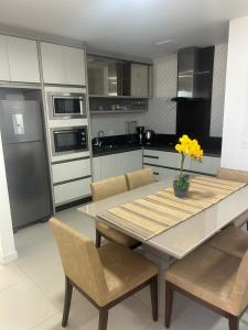 una cucina con tavolo e sedie e una cucina con elettrodomestici di Cobertura com jacuzzi e churrasqueira privada - Praia dos Ingleses a Florianópolis