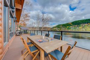 a wooden table and chairs on a deck with a view of a lake at Le Tresor du Lac in Mandeville