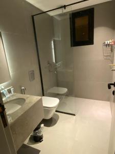 een badkamer met toilet en glazen douche bij Velora Serviced Apartments in Al Khobar