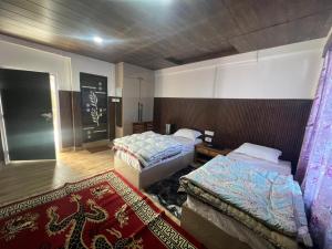 a hotel room with two beds and a rug at Maitreya Homestay in Tawang
