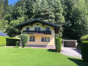a yellow house with a balcony on a yard at Haus Monterosa in Sankt Johann im Pongau
