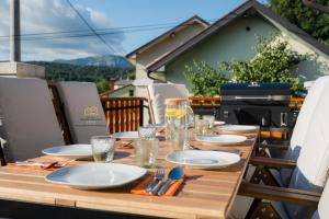 una mesa de madera con platos y vasos en el balcón en Spacious Apartment Senozece - with terrace & grill, en Senožeče