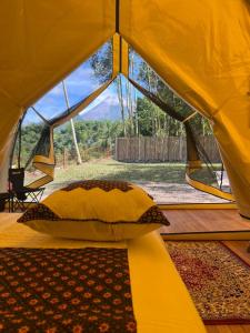 a tent with a pillow and a view of a field at Kayi glamping in Kaliurang