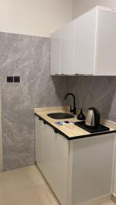 شقق رحابة المكان للشقق المفروشه في الخرج: مطبخ مع دواليب بيضاء وغلاية شاي على الكاونتر +11 صورة