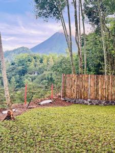 una staccionata di legno in un campo con le montagne sullo sfondo di Kayi glamping a Kaliurang Altre 2 foto