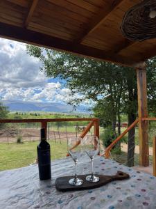 een tafel met een fles wijn en twee wijnglazen bij Cabaña Zara in Villa Yacanto +8 foto's