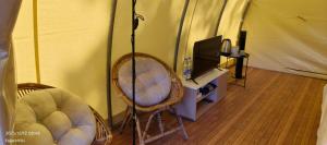 a room with two chairs and a tv in a tent at Kayi glamping in Kaliurang