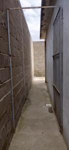 ein leerer Flur mit einer Backsteinmauer und einem Tor in der Unterkunft Casa de 01 quarto para temporada in Marataizes