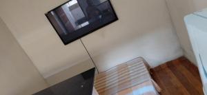 einen Flachbild-TV an einer Wand mit einer Bank in der Unterkunft Casa de 01 quarto para temporada in Marataizes