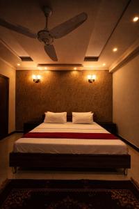 a bedroom with a bed with a ceiling fan at Hill Town Family Suites in Islamabad
