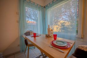 a dining room table with plates and glasses and a window at Appartement Dauphin - Résidence Kiwi in Aytré
