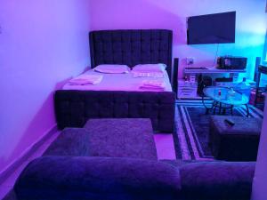 een slaapkamer met een bed en een tafel met violette lampen bij Goshen heights in Kitengela  +2 foto's