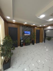 an empty lobby with plants and a tv on a wall at NiNi HOSTEL in Tashkent