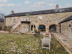 een stenen huis met twee banken ervoor bij The Classic in Falstone