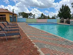 a group of chairs sitting next to a swimming pool at Emlomo logde in Ermelo