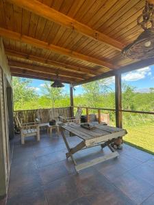 een picknicktafel op een veranda met een houten dak bij Cabaña Zara in Villa Yacanto