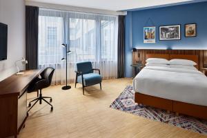 a hotel room with a bed and a desk and chair at Four Points by Sheraton Munich Messe in Munich +36 photos
