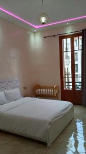 Dormitorio con cama blanca con iluminación rosa en Appartement Néoclassique centre -ville, en Casablanca