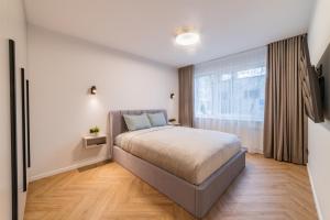 een slaapkamer met een bed en een groot raam bij ENZO Apartments in Šiauliai
