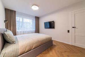 een slaapkamer met een bed en een tv aan de muur bij ENZO Apartments in Šiauliai
