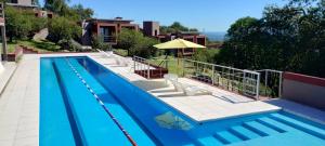 een groot zwembad met stoelen en een parasol bij Crepúsculo Serrano in Merlo