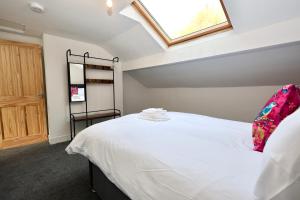 Schlafzimmer mit einem großen weißen Bett und einem Dachfenster in der Unterkunft Nursery House Retreat in Heptonstall