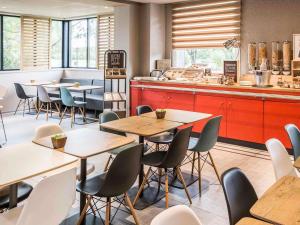 a restaurant with tables and chairs and a counter at ibis Rennes Cesson in Cesson-Sévigné