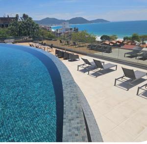 vista su una piscina con sedie e sull'oceano di Cobertura com jacuzzi e churrasqueira privada - Praia dos Ingleses a Florianópolis