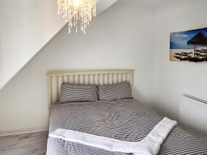 Posto letto in una camera bianca con lampadario pendente. di Oasis a Hythe Altre 6 foto