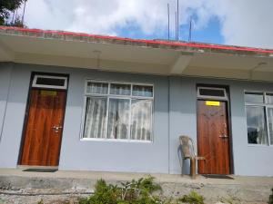 ein Haus mit zwei Türen und einem Stuhl davor in der Unterkunft SILVERBERRY Homestay in Kalimpong