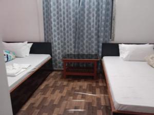 ein Zimmer mit zwei Betten und einem Tisch darin in der Unterkunft SILVERBERRY Homestay in Kalimpong