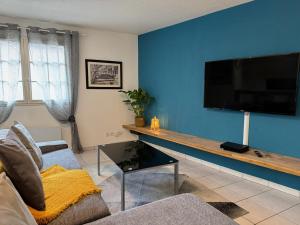 een woonkamer met een flatscreen-tv aan een blauwe muur bij Rives Bleues by PRIM0 C0NCIERGERIE in Pont-du-Château +5 foto's