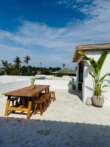 een houten tafel en banken op een patio bij Gypsea Rest Villa in Nusa Lembongan