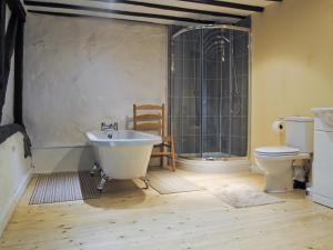 een badkamer met een bad, een toilet en een wastafel bij Hirros Hall Longhouse in Llanerfyl