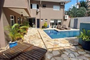 a house with a swimming pool in front of a house at Hotel Casarão Pitangueiras in Guarujá