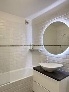 een witte badkamer met een wastafel en een spiegel bij Rives Bleues by PRIM0 C0NCIERGERIE in Pont-du-Château