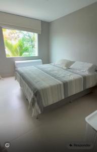 een bed in een witte kamer met een raam bij Casa Oliveira in Cayru