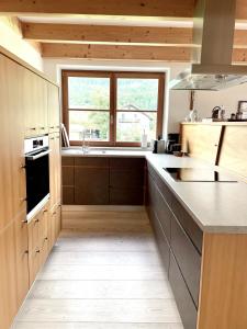 una cucina con armadi in legno e una grande finestra di Maisonette in Kuchl, Pure nature a Kuchl Altre 16 foto