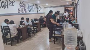 a woman standing in a restaurant with people sitting at tables at The Mount City Near US Consulate in Chennai +44 photos