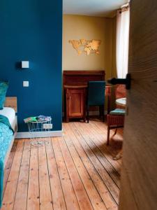 een woonkamer met blauwe muren en een houten vloer bij Au Vent des Blés in Incourt