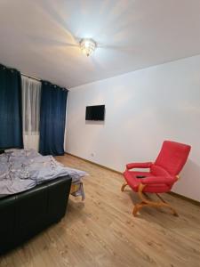 Schlafzimmer mit einem roten Stuhl und einem Bett in der Unterkunft Apartament ultracentral Ștefan cel mare in Craiova