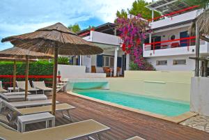 Una piscina con sillas y una sombrilla al lado de un edificio. en Villa Giulia con piscina vista mare, en Sperlonga