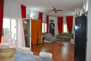 sala de estar con cortinas rojas, mesa y sillas en Villa Giulia con piscina vista mare, en Sperlonga