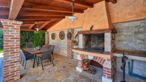 a patio with a brick fireplace and a table and chairs at Rustic Villa Simone with outdoor pool in Porec in Krmenjak