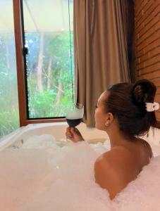 Terra Verde Visconde de Mauá في فيسكوندي دي ماوا: امرأة جالسة في حوض الاستحمام عقد كوب من النبيذ