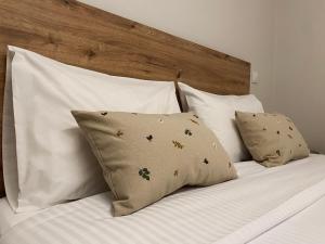 a bed with white pillows and a wooden headboard at Abete Luxury Apartments in Metsovo
