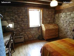 een slaapkamer met een stenen muur, een bed en een raam bij La Sauvagine in Les Fourgs