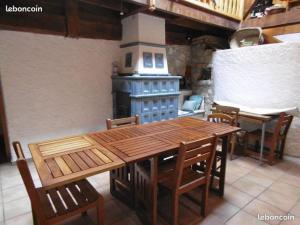 een houten tafel en stoelen in een keuken met een fornuis bij La Sauvagine in Les Fourgs